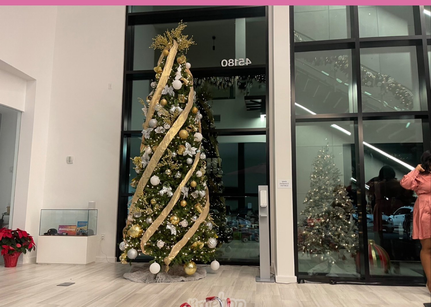 Tall ribboned Christmas tree in a glass lobby